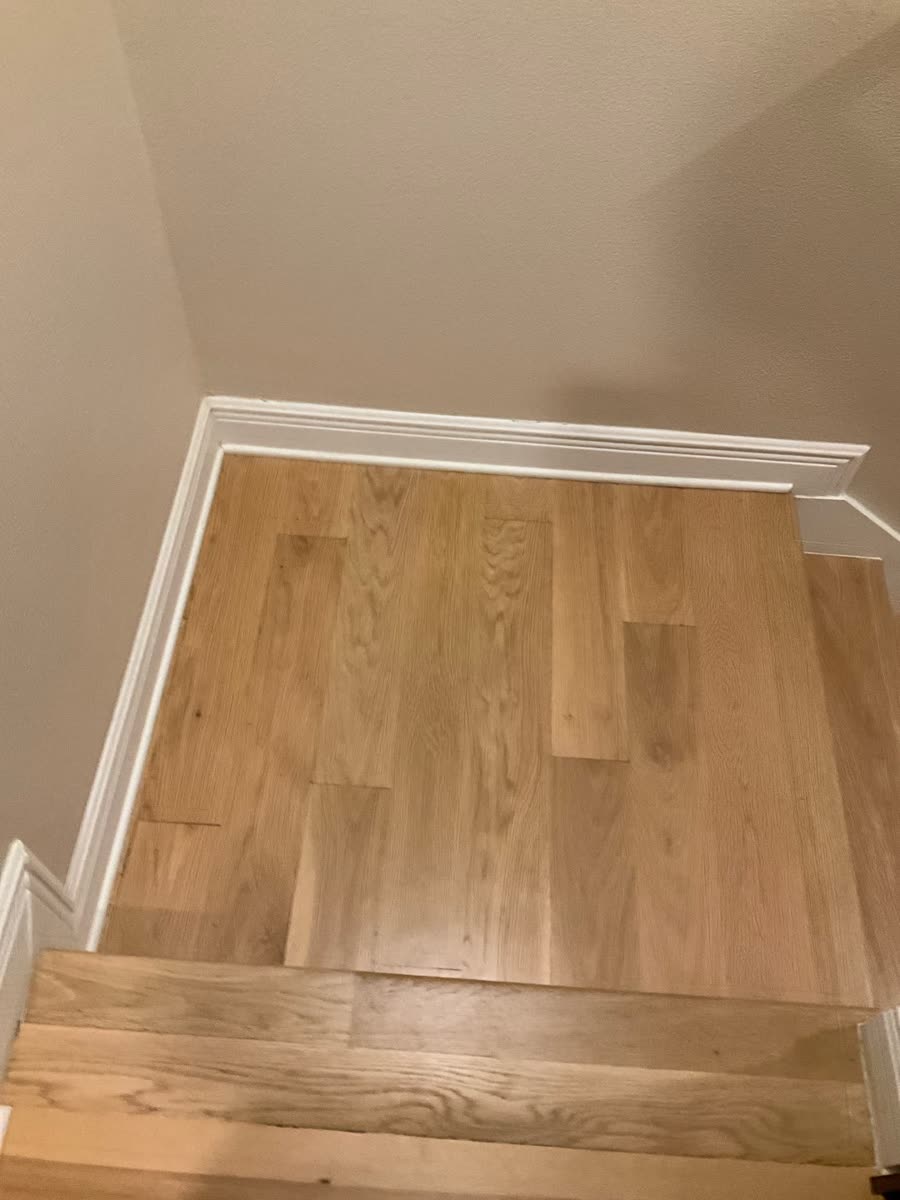 refinished oak hardwood stair landing with baseboard